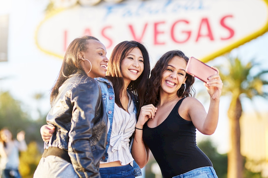 visitors pose for photo beside the Las Vegas welcome sign